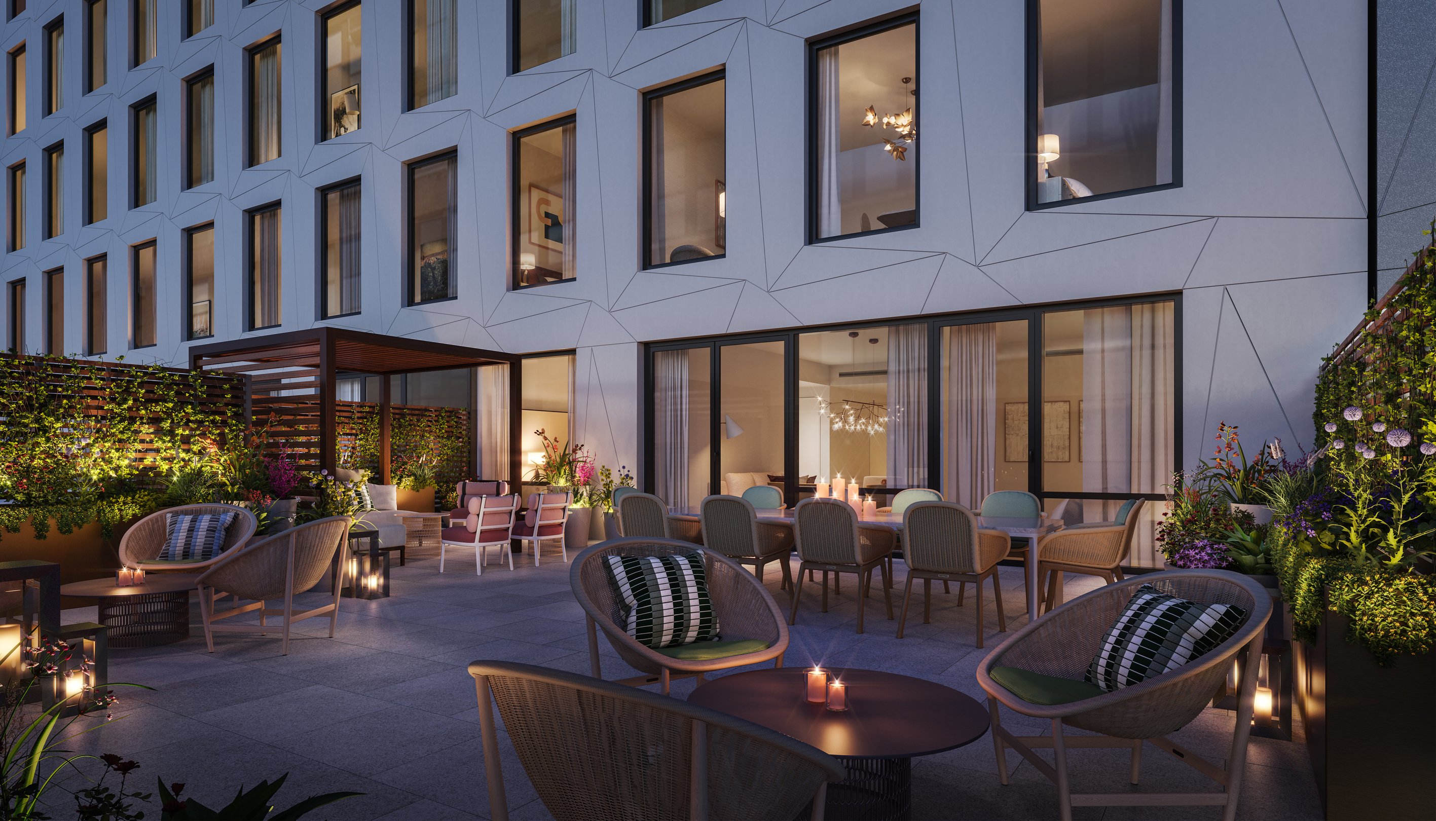 An outdoor patio with tables, chairs and plants backing the sliding back door of one of the garden residences