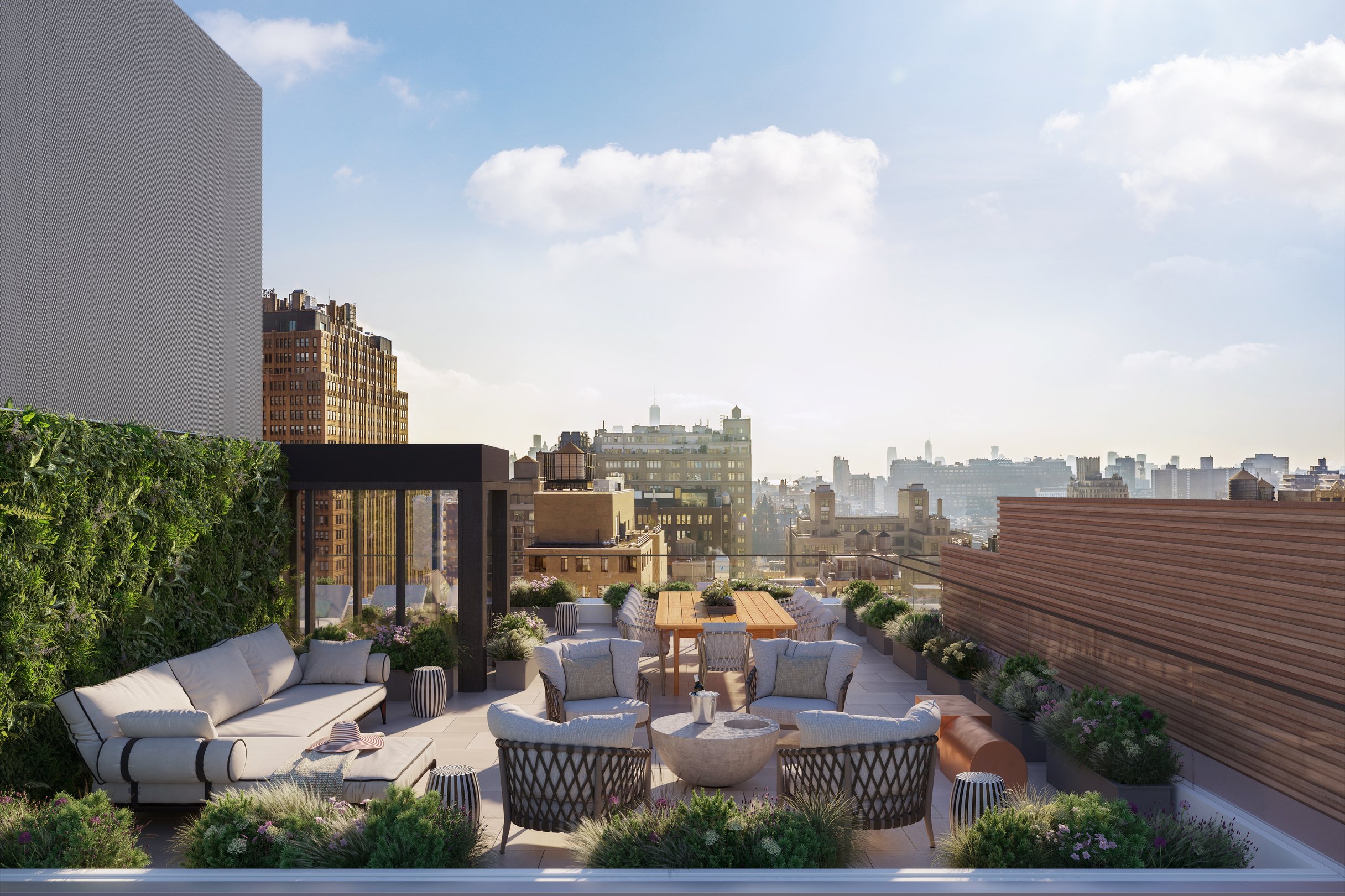 A rooftop patio with couches, chairs, one smaller table with a bucket of ice and a wine bottle and a larger wooden table with 9 chairs around it. Square plant holders with green plants and flowers line the sides of the space with a glass ledge overlooking the city. The side of the space connected to the building has a wall of green ferns that meet a sheltered entrance.